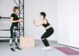 A trainer coaching proper squat form to help prevent injury during strength training